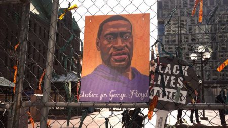 A picture of George Floyd hangs on a fence barrier that surrounds the Hennepin County Government Center in Minneapolis during the trial of former police officer Derek Chauvin in March. The Justice Department is now bringing criminal charges against Chauvin over allegedly violating Floyd's rights and using excessive force in restraining him.