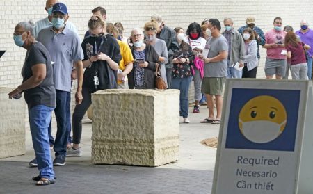 Wearing masks to prevent the spread of COVID-19, voters line up to cast their ballot during early voting in April in Mansfield, Texas. Under Gov. Abbott's new order, counties won't be able to require masks at voting sites.