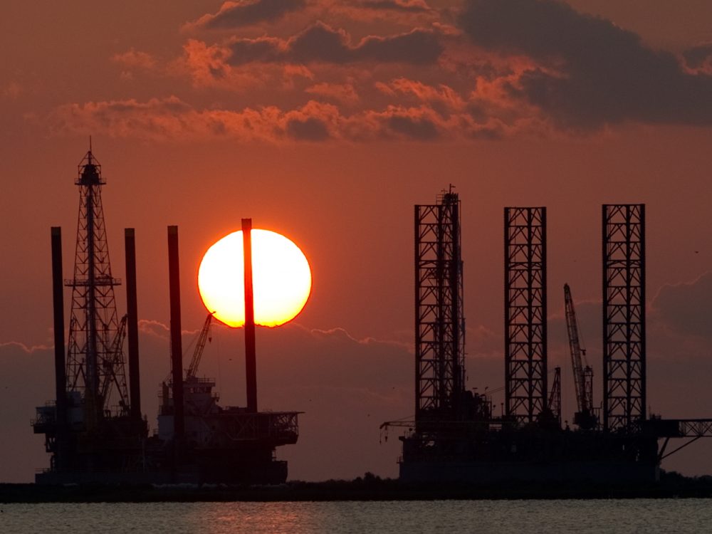 The energy industry was shaken by a trio of events this week that could help shape the future of oil and gas. Here, the sun sets behind two under-construction offshore oil platform rigs in Port Fourchon, La., in 2010.