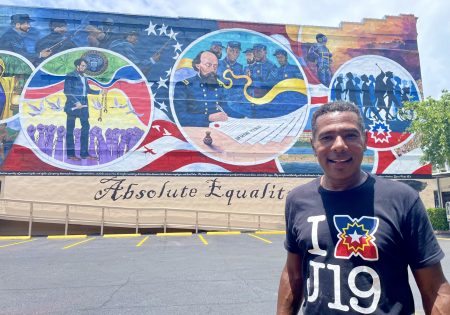 Houston-based public artist Reginald C. Adams stands in front of his Juneteenth mural "Absolute Equality" in Galveston, Texas.