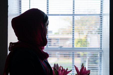 The daughter of a slain Afghan interpreter referred to as "Mohammad" stands at the window inside her family's new apartment in Houston on June 17, 2021.