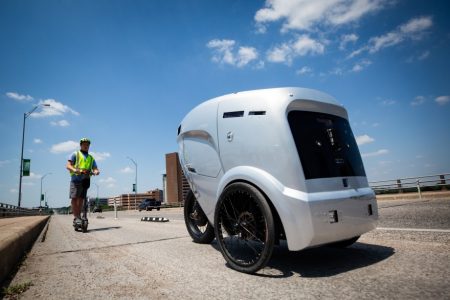 Riley Pakes, with Refraction AI, monitors a delivery robot in a bicycle lane on South Congress Avenue. Attitudes differ among cyclists on whether they should share bike lanes with the robots.