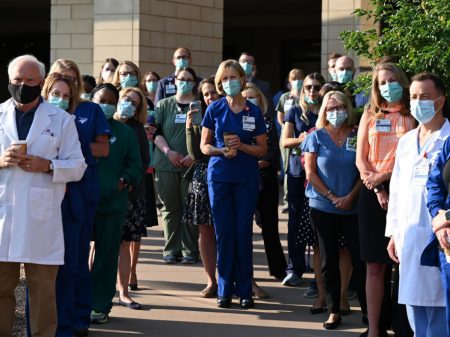 Front-line workers at a medical center in Aurora, Colo., gather for a COVID-19 memorial on July 15 to commemorate the lives lost in the coronavirus pandemic. New estimates say many thousands more will die in the U.S. this summer and fall.