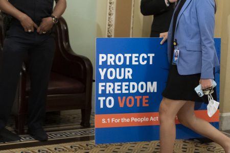 An aide carries a sign to the Senate floor as the Senate prepares for a key test vote on the For the People Act, a sweeping bill that would overhaul the election system and voting rights, at the Capitol in Washington, Tuesday, June 22, 2021. The bill is a top priority for Democrats seeking to ensure access to the polls and mail in ballots, but it is opposed by Republicans as a federal overreach. (AP Photo/Alex Brandon)