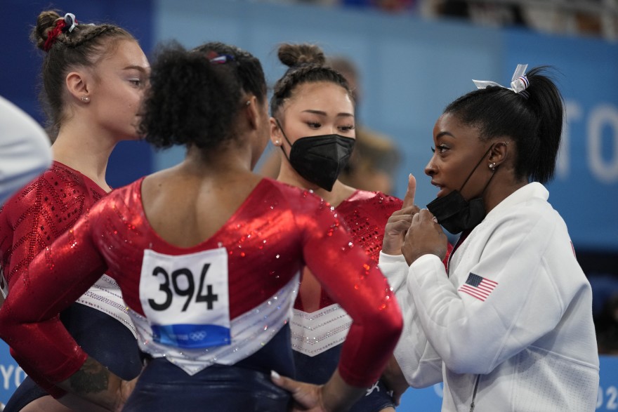 Simone Biles, of the United States, talks to teammates Jordan Chiles, back to camera, Sunisa Lee and Grace Mc Callum, left, prior to the uneven bars competition during the artistic gymnastics women's final at the 2020 Summer Olympics, Tuesday, July 27, 2021, in Tokyo.