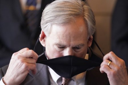 Texas Gov Greg Abbott removals his mask before speaking at a news conferenced about migrant children detentions Wednesday, March 17, 2021, in Dallas.