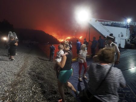 People evacuate from a wildfire north of Athens, Greece, on Friday. A climate-driven heat wave helped create conditions for the fire to burn out of control. Scientists warn that humans are running out of time to curb greenhouse gas emissions and avoid catastrophic global warming.