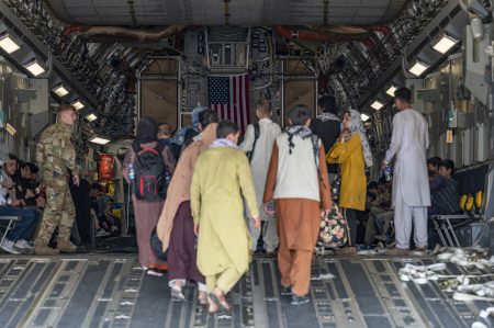 In this image provided by the U.S. Air Force, a U.S. Air Force loadmaster, assigned to the 816th Expeditionary Airlift Squadron, assists evacuees aboard a C-17 Globemaster III aircraft in support of Operation Allies Refuge at Hamid Karzai International Airport in Kabul, Afghanistan, Friday, Aug. 20, 2021.