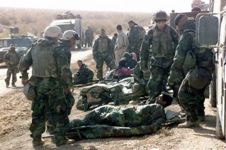 US Marine Corps (USMC) personnel assigned to 1st Regimental Combat Team (RCT1), administer aid to injured Marines, Iraqi civilian, and Iraqi soldiers after battling to clear the Main Supply Route (MSR) on Route 7, in the vicinity of An Nasiriyah, Iraq during the Iraq War.