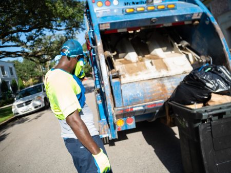 A Republic Services worker in Houston assists with garbage collection on a summer afternoon. The company has been fined in the wake of heat-related deaths of workers but says it has implemented prevention policies. This worker was not interviewed for the story.