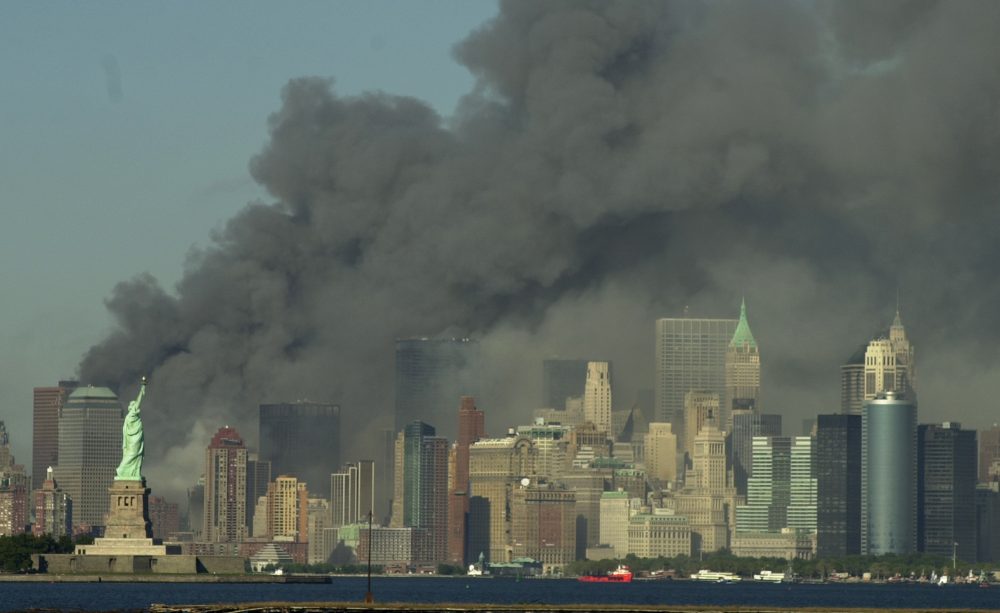 Thick smoke billows into the sky from the area behind the Statue of Liberty, lower left, where the World Trade Center towers stood, on Tuesday, Sept. 11, 2001.  The towers collapsed after terrorists crashed two planes into them. 