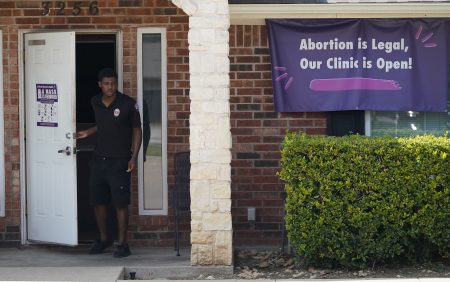 In this Wednesday, Sept. 1, 2021 file photo, a security guard opens the door to the Whole Women's Health Clinic in Fort Worth, Texas.