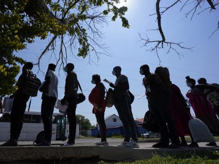 In this June 16, 2021, file photo migrants stand stand in line at a respite center after they crossed the U.S.-Mexico border and turned themselves in and were released in Del Rio, Texas.