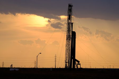 A drilling rig at sunset operates on the north side of Midland.