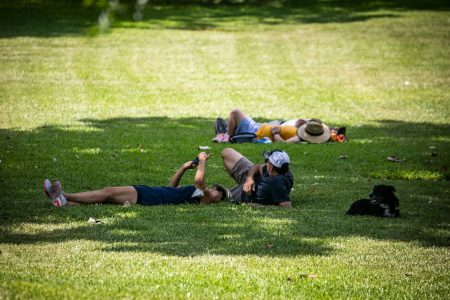 People rest in the shade outside the Texas Capitol on a hot day in July. Texans can likely expect more triple-digit days in the future, according to a new report.