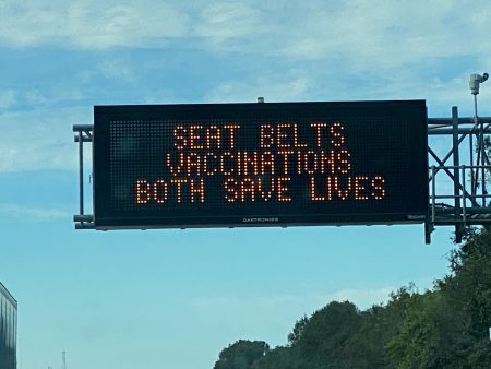 Signs that display "Seat Belts, Vaccinations Both Save Lives" can be seen along I-10 in Louisiana. This photo was taken between Lafayette and Lake Charles.