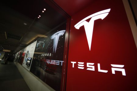 FILE - This Feb. 9, 2019, file photo shows a sign bearing the company logo outside a Tesla store in Cherry Creek Mall in Denver. A driver was behind the wheel when a Tesla electric car crashed and burned last April in Houston, killing two men, neither of whom was found in the driver’s seat. The U.S. National Transportation Safety Board announced the findings in an investigative report released Thursday, Oct. 21, 2021 on the April 17 crash on a residential road in Spring, Texas.