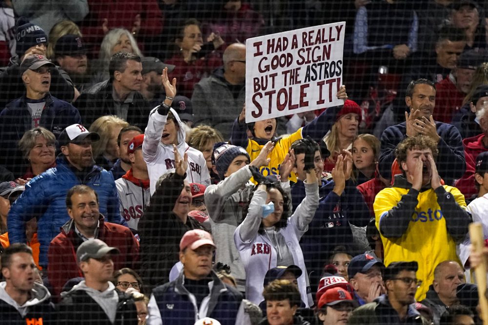 FILE - A Boston Red Sox fan holds a sign up during the second inning in Game 3 of baseball's American League Championship Series against the Houston Astros in Boston, in this Monday, Oct. 18, 2021, file photo. Before they could swing away against the Atlanta pitchers in the World Series, Jose Altuve and Houston Astros face another kind of heat. No, the cheating scandal that tainted their 2017 championship isn't going away anytime soon.