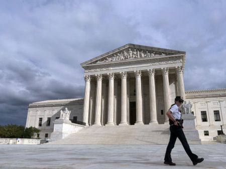 A police officer walks by during a voting rights rally, at the U.S. Supreme Court Thursday, Oct. 28, 2021, in Washington.