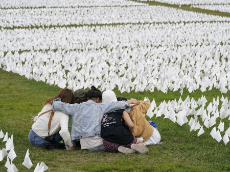 FILE - In this Sept. 21, 2021, file photo, visitors sit among white flags that are part of artist Suzanne Brennan Firstenberg's "In America: Remember," a temporary art installation to commemorate Americans who have died of COVID-19, on the National Mall in Washington. Firstenberg was struck by how strangers connected in their grief at the installation, which ended Oct. 3.