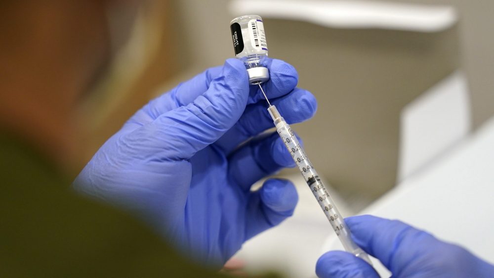 A health care worker fills a syringe with the Pfizer COVID-19 vaccine.