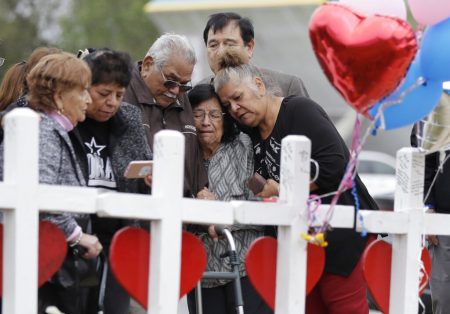 In this Nov. 10, 2017, file photo, family and friends gather around a makeshift memorial for the victims of the First Baptist Church shooting at Sutherland Springs Baptist Church in Sutherland Springs, Texas.
