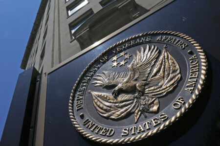 FILE - This June 21, 2013, file photo, shows the seal affixed to the front of the Department of Veterans Affairs building in Washington.  In a federal lawsuit filed this week, U.S. Navy veteran from South Carolina says he ended up with “full-blown AIDS,” because government health care workers never informed him of his positive test result in 1995. He says the test was done as part of standard lab tests at a U.S. Department of Veterans Affairs medical center in Columbia, South Carolina. A V.A. spokeswoman says the agency typically does not comment on pending litigation.