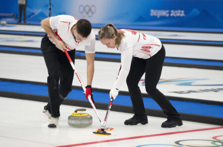 Canada's Rachel Homan and John Morris sweep a rock as they face Britain's Bruce Mouat and Jennifer Dodds in mixed doubles curling play at the 2022 Winter Olympics in Beijing on Thursday, Feb. 3, 2022.