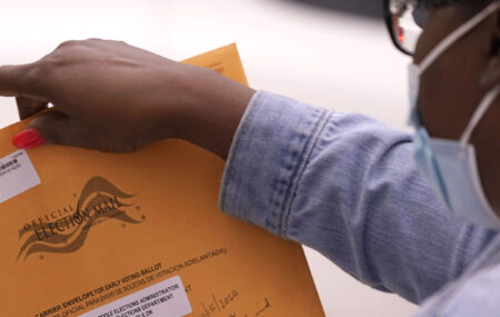 A mail-in ballot is accepted by election workers at Dallas County ballot collection point Thursday, Oct. 15, 2020, in Dallas. A federal appeals court has reinstated a limit on the number of ballot drop-off locations in Texas to one per county.