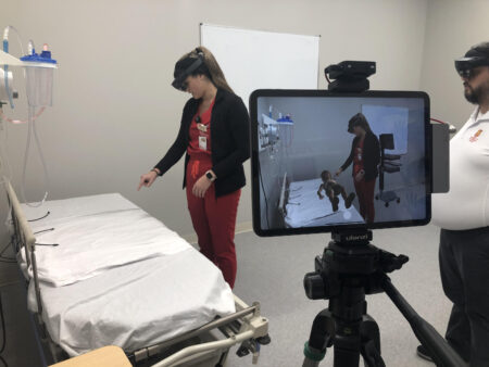 In the pediatric simulation, Nursing Student Reagan Pair uses a holographic stethoscope to listen to the heart and lungs of a 5-year-old boy.