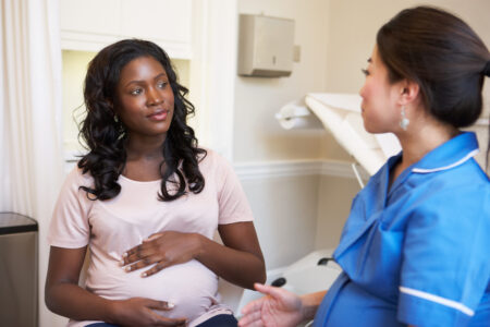 Pregnant Woman Meeting With Nurse In Clinic