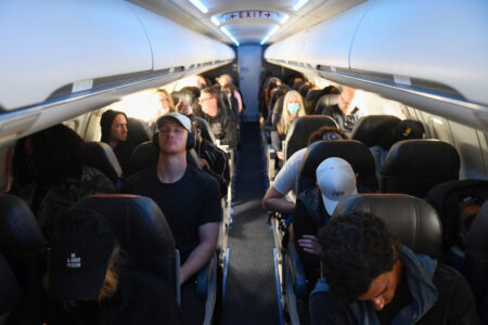 Airline passengers, some not wearing face masks following the end of Covid-19 public transportation rules, sit during a American Airlines flight operated by SkyWest Airlines from Los Angeles International Airport (LAX) in California to Denver, Colorado on April 19, 2022. - Mask mandates on public transportation are no longer in effect following a ruling by federal judge on April 18, 2022. (Photo by Patrick T. FALLON / AFP) (Photo by PATRICK T. FALLON/AFP via Getty Images)