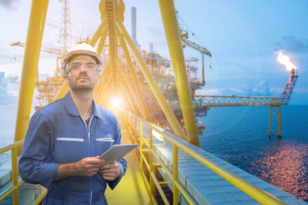 Caucasian man engineer staff worker with tablet in hand and offshore rig background