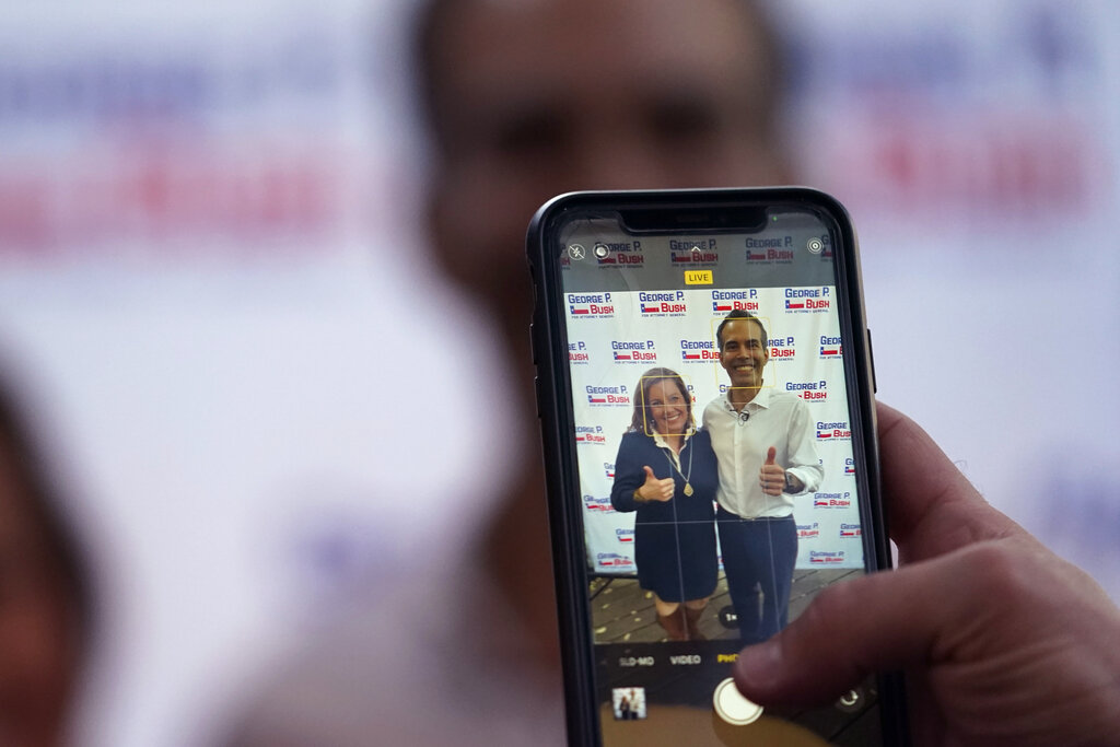 Texas Land Commissioner George P. Bush, right, poses for photos during a campaign stop, Thursday, Feb. 10, 2022, in Austin, Texas. The 45-year-old son of former Florida Gov. Jeb Bush is running for attorney general in Texas' first-in-the-nation primary Tuesday, March 1, 2022.
