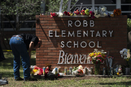 A law enforcement personnel lights a candle outside Robb Elementary School in Uvalde, Texas, Wednesday, May 25, 2022.