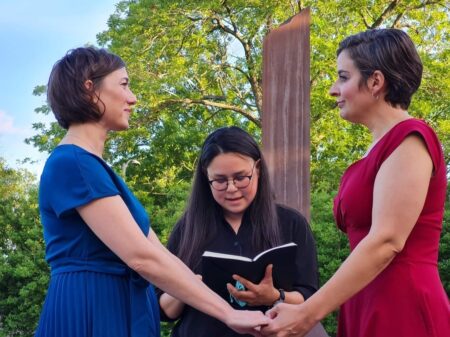 Carlie Brown (left) and Molly Pela exchange wedding vows as their friend, Julie Takahashi, officiates the ceremony. Both women said they rushed to get married after reading Supreme Court Justice Clarence Thomas' concurring opinion in striking down Roe v. Wade, in which he suggested also overturning the landmark case that legalized same-sex marriage.
