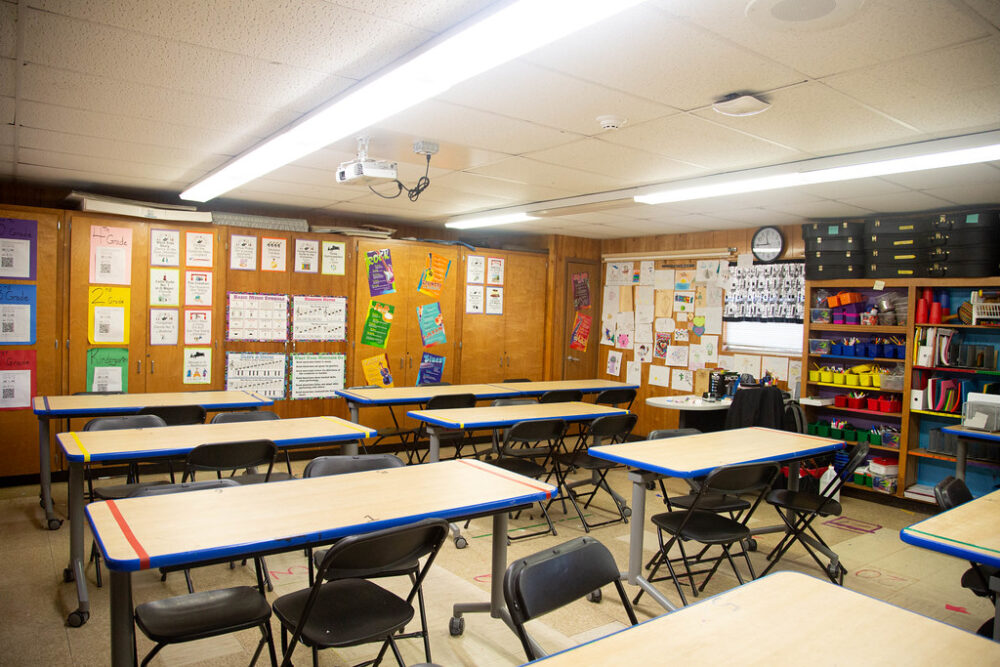 An empty classroom with tables and chairs