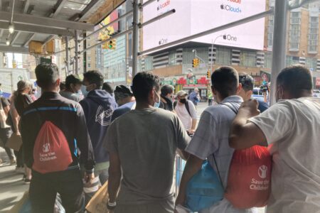 Asylum-seekers who have recently arrived in New York on a bus from Texas wait for ride-share vehicles, organized by a mutual aid group, to take them into the city.