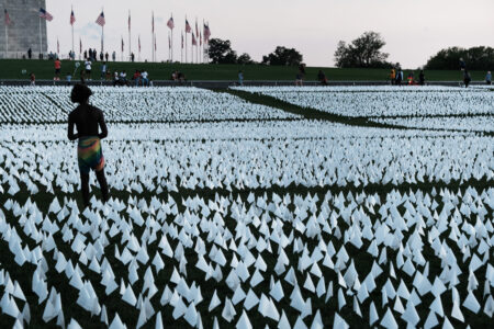 WASHINGTON, DC - SEPTEMBER 18: Visitors walk through 'In America: Remember,' a public art installation commemorating all the Americans who have died due to COVID-19 near the Washington Monument on September 18, 2021 in Washington, DC. The concept of artist Suzanne Brennan Firstenberg, the installation includes more than 660,000 small plastic flags, some with personal messages to those who have died, planted in 20 acres of the National Mall. (Photo by Spencer Platt/Getty Images)