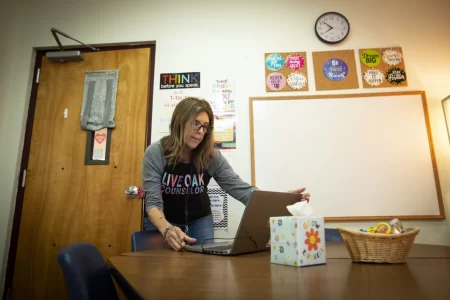 Elise Harris, a counselor at Live Oak Elementary School in the Round Rock Independent School District, sets up a laptop used to provide telemedicine services in her office.