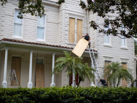 Two people work on boarding up a house in South Tampa Bay Florida before Hurricane Ian hits the area on September 27, 2022.
Carlos Osorio for NPR