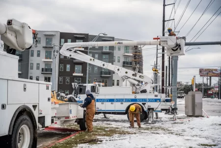 Electrical workers repair a power line in Austin on Feb. 18, 2021, during a winter storm that caused massive blackouts across Texas. The state Sunset Advisory Commission says the agency that oversees the power grid needs more resources to help prevent a similar disaster.