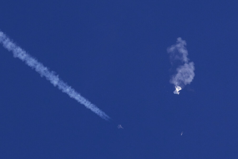 A fighter jet flies near the remnants of a large balloon after it was struck by a missile over the Atlantic Ocean, just off the coast of South Carolina near Myrtle Beach, Saturday, Feb. 4, 2023. The downing of the suspected Chinese spy balloon by a missile from an F-22 fighter jet created a spectacle over one of the state’s tourism hubs and drew crowds reacting with a mixture of bewildered gazing, distress and cheering. 