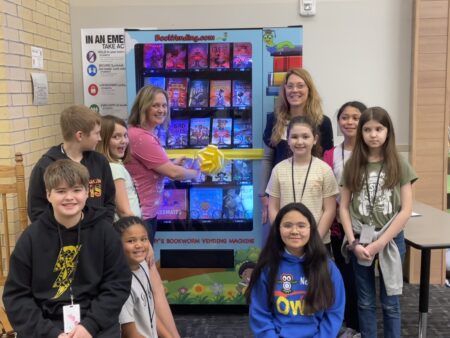 Students at Nelson Elementary in Alvin ISD stand in front of a book vending machine. The machine is used as a reward system and doesn't take money, rather special tokens given to the students.
