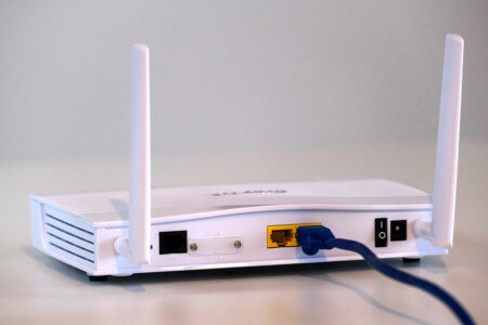 A white WiFi router with a blue wire coming out of the back.