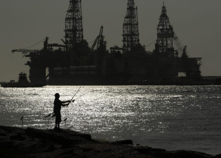 FILE - A man fishes near an oil drilling platform on May 8, 2020, in Port Aransas, Texas. Offshore oil and gas operations in the Gulf of Mexico are releasing far more climate-changing methane than official estimates show, according to a new study published Monday, April 3, 2023.
