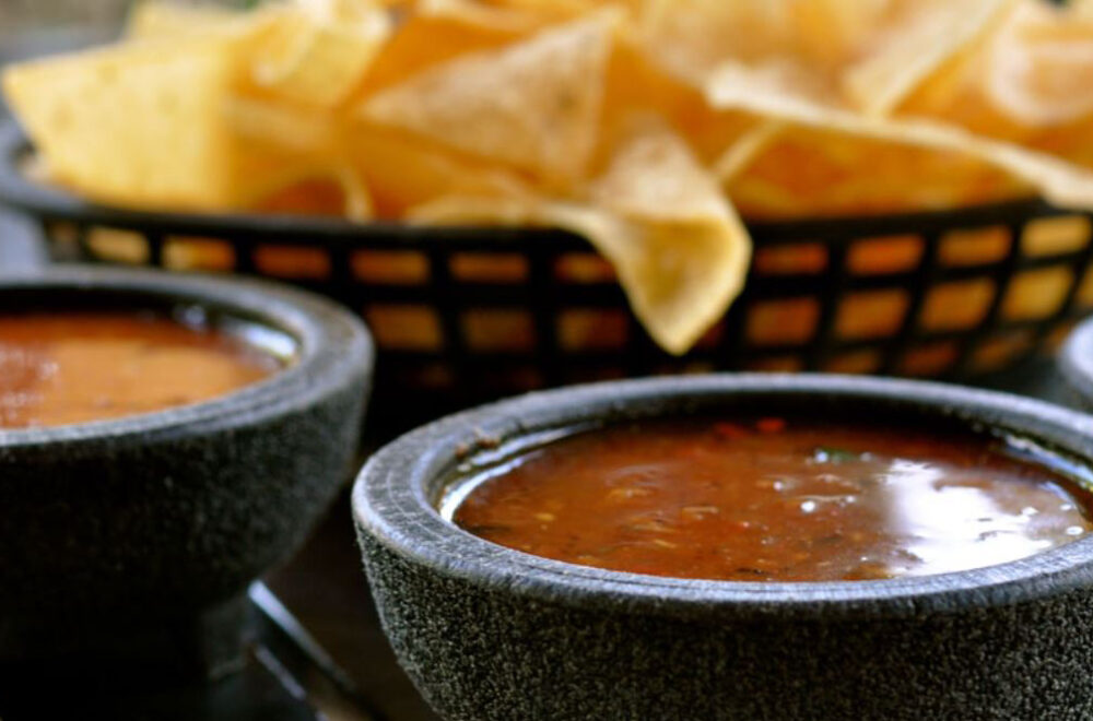 A bowl of salsa next to some tortilla chips