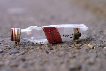 An empty miniature bottle that once contained liquor rests on a street near a sidewalk, Monday, April 3, 2023, in Boston.  A Boston city councilor has proposed barring city liquor stores from selling the single-serve bottles that hold 100 milliliters or less of booze both as a way to address alcohol abuse and excessive litter.