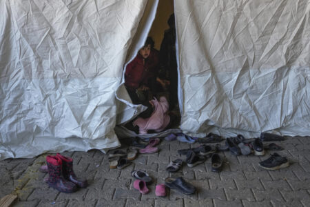A child peeks out from inside a tent shelter in Turkey.