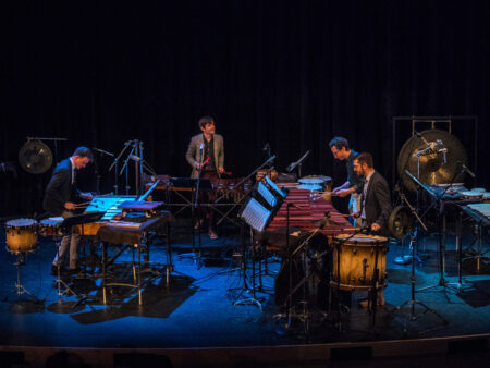 Photo of percussionists performing on stage with several instruments